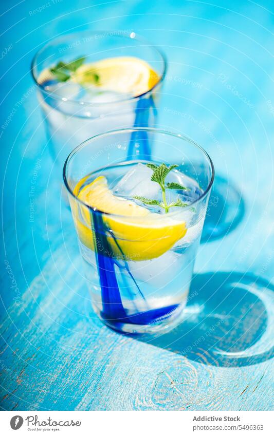 Summer cocktail with lemon vodka, slice of lemon and wild mint leaves summer leaf table surface beverage glass transparent cube cool refreshment liquid drink