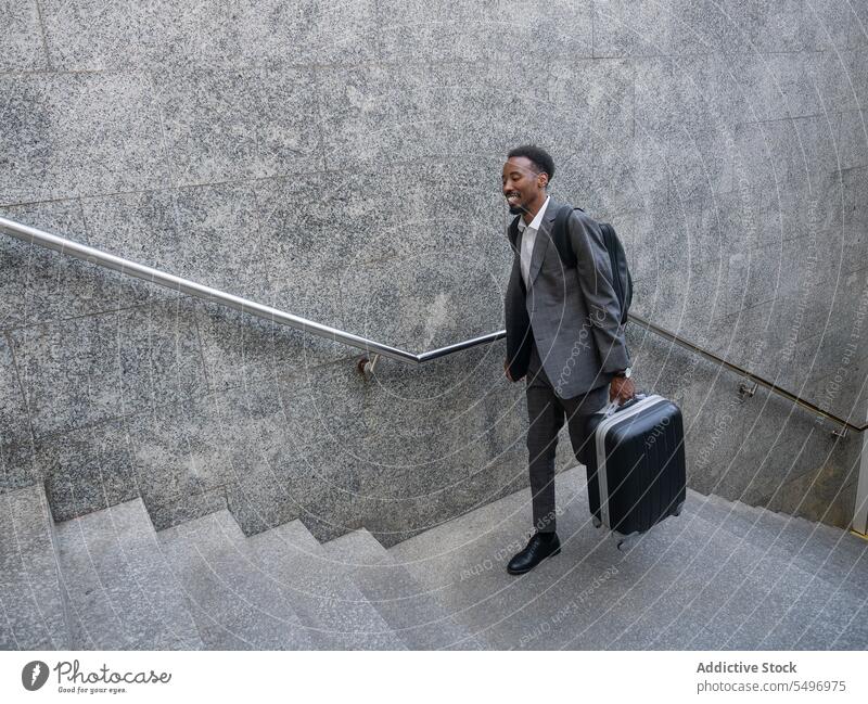Cheerful black man with suitcase walking upstairs underground happy formal staircase stairway businessman male cheerful luggage african american baggage