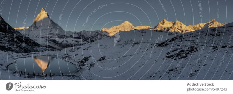 Snowy mountains near lake under dark sky at sunrise in winter day landscape snow nature rocky peak picturesque ridge cold calm scenic range highland scenery