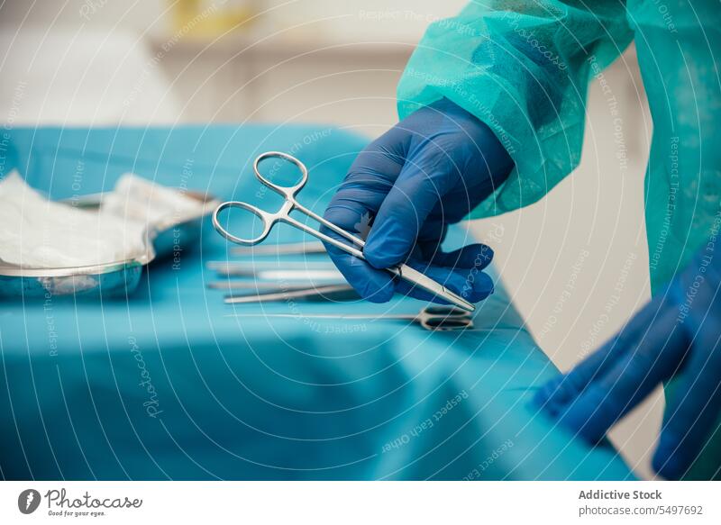 Crop doctor arranging surgical instruments on table before operation man surgeon surgery tool prepare sterile medical operating room professional glove hospital