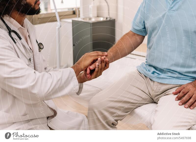 Anonymous doctor and patient shaking hands men health care handshake clinic hospital professional medical physician attentive black african american male job