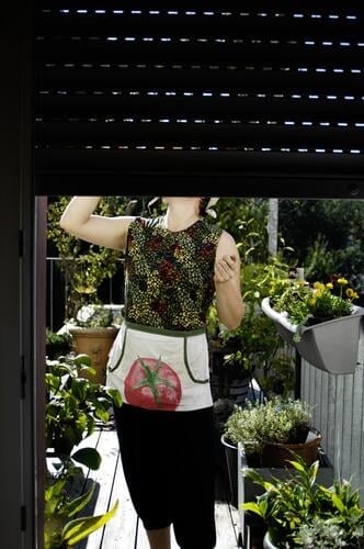 Woman standing on the balcony drinking something, her face is covered by the shutter of the balcony door Terrace green plants Garden Potted plants Gardening