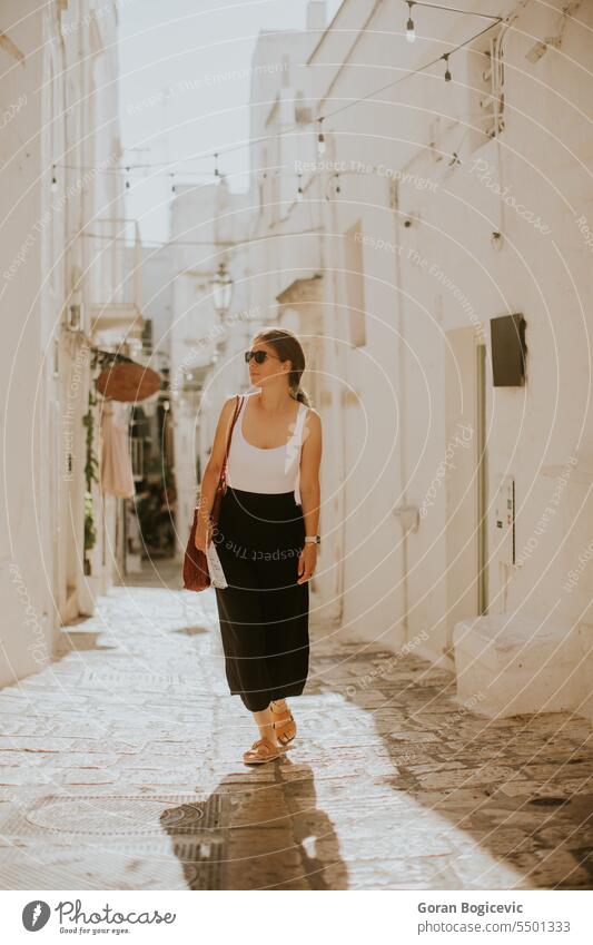 Female tourist with paper city map on narrow streets of Ostuni, Italy woman female tourist map direction navigation exterior tourism house building summer
