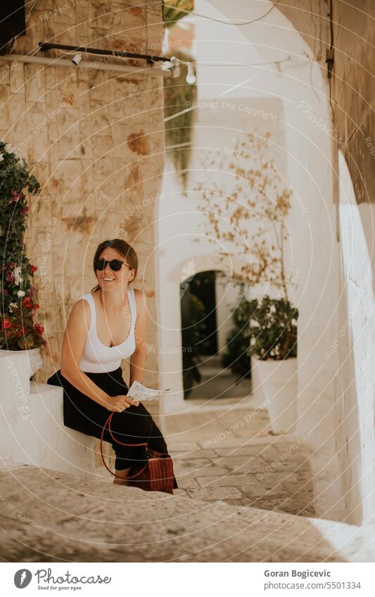 Female tourist with paper city map on narrow streets of Ostuni, Italy alley alleyway ancient apulia architectonic architecture building center destination