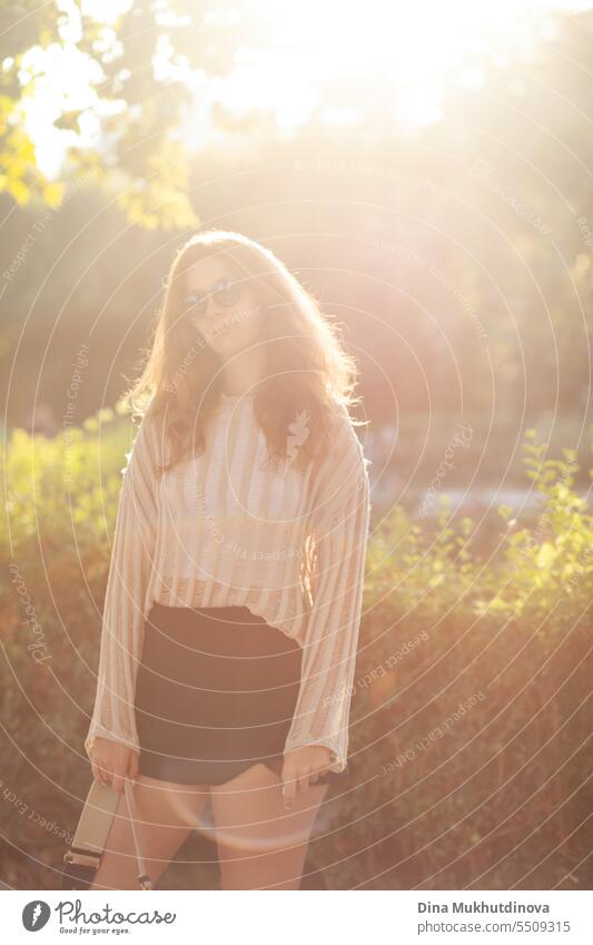 candid portrait of young beautiful woman in sunglasses backlit with sunlight in summer. Pretty ginger girl with red hair. park smiling happy pretty Smiling