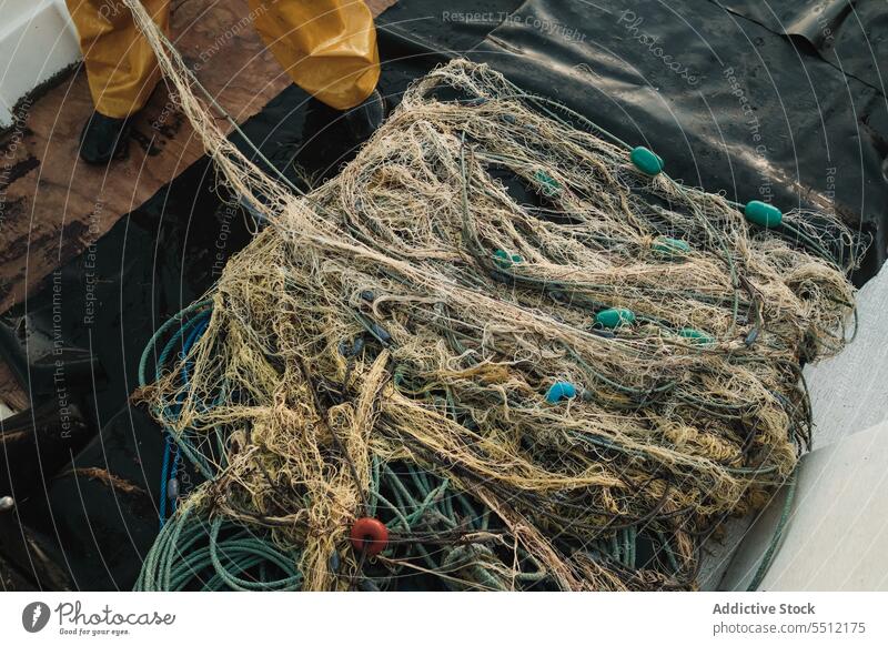 Heap of tangled fishing net on deck of sailboat in daylight rope equipment marine seawater transport vessel ocean cruise navigate outside float moor ripple