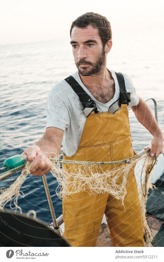 Fisherman fishing in open sea from sail boat fisherman net schooner work uniform focus male soller balearic islands mallorca seine fish hunt trawler