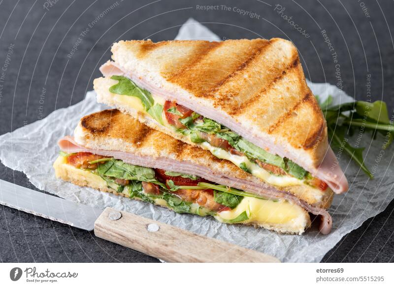 Panini sandwich with ham, cheese, tomato and arugula on black slate background bread cooked fast food grain grilled horizontal italian leaf lunch meal panini