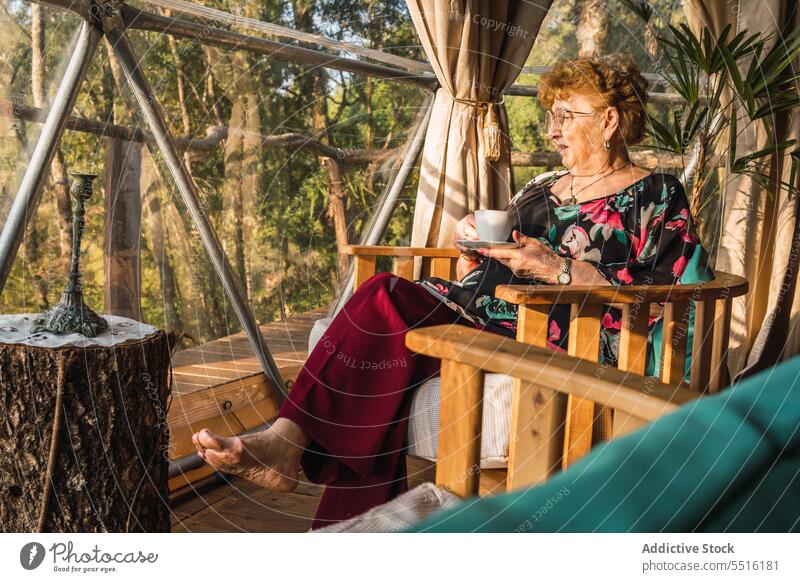 Senior woman resting in glamping dome leisure hot drink vacation pensioner senior lounge armchair elderly tea countryside cup relax beverage coffee mug comfort