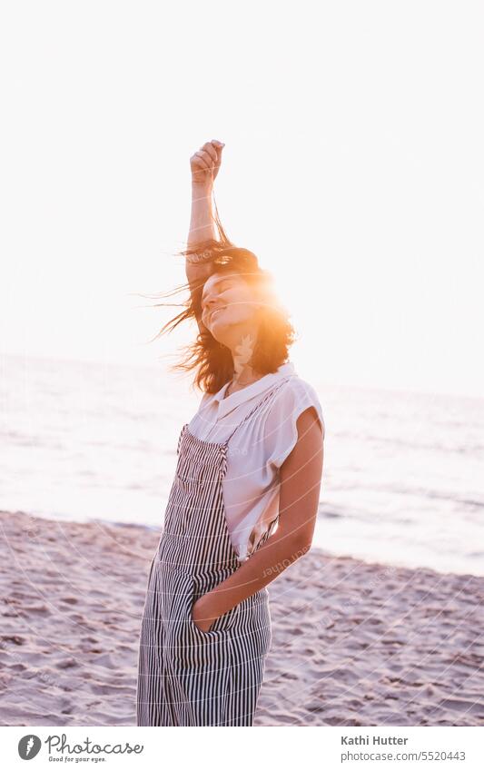 A young woman by the sea with wind in her hair and the sunset. Sunset Woman Beach Ocean Evening Water Human being Sky Silhouette Shadow Twilight Colour photo