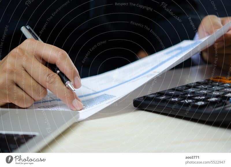 Businessperson reviewing documents with pen, analyzing data on graph report statistic and chart finance, budget, investment, accountant, diagram on desk.