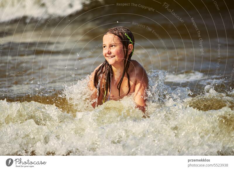 Little girl playing with waves in the sea. Kid playfully splashing with waves. Child jumping in sea waves. Summer vacation on the beach summer vacations ocean