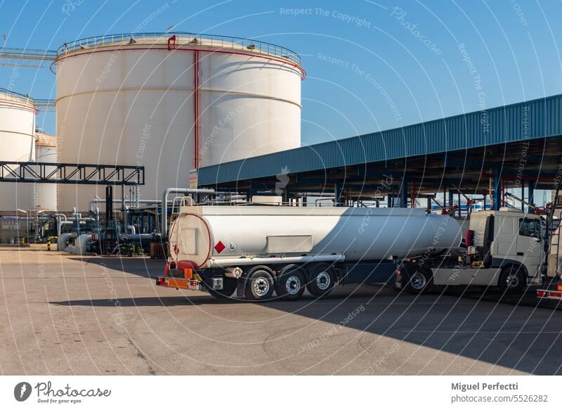 Fuel tanker truck entering to load at a loading dock, with the huge storage tanks in the background. fuel transport flammable terminal factory deposit vehicle