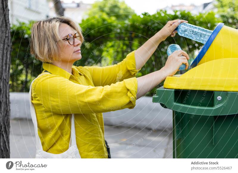 Woman throwing out trash in yellow bin recycle plastic garbage carry ecology problem casual rubbish daylight waste container reduce package utilize litter junk