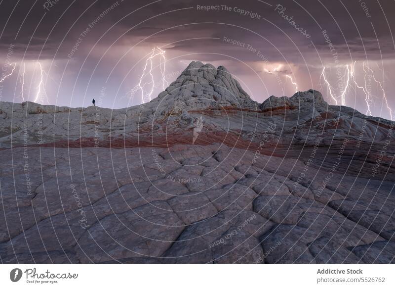 Anonymous tourist standing on rocky mountains under stormy sky highland traveler admire nature boulder white picket ridge landscape hike lightning cloudy sky