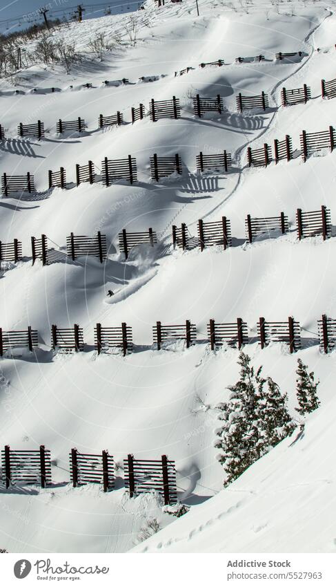 Snowy hill slope with wooden fences in winter ski resort snow sport activity slide hobby active mountain cold extreme lifestyle wintertime practice training