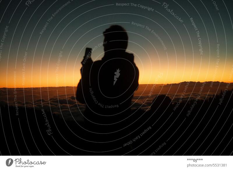 Man filming sunset on mountain above clouds with cell phone Sky Clouds Take a photo Filming outlook Vantage point Twilight Mystic Light Evening Contrast Sunset