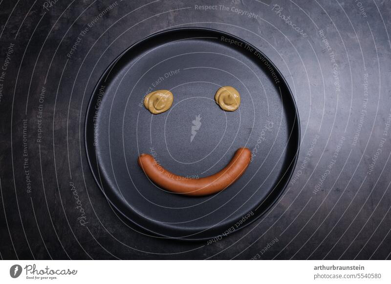 Fresh crispy wiener positioned on black plate with mustard as smiley face Sausage sausage Sausage kitchen Nutrition Food industry food food products Eating