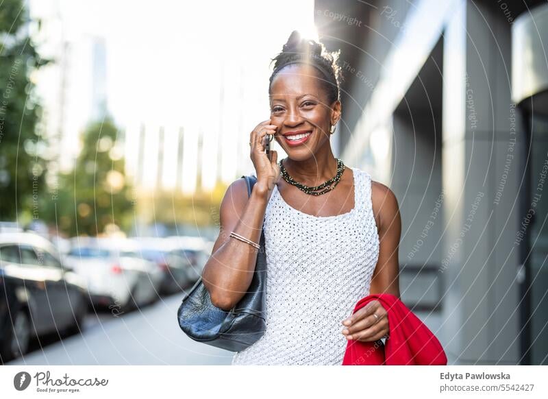 Portrait of smiling mature business woman using cell phone in urban environment people Downtown Businesswoman Joy Woman Black naturally Attractive City