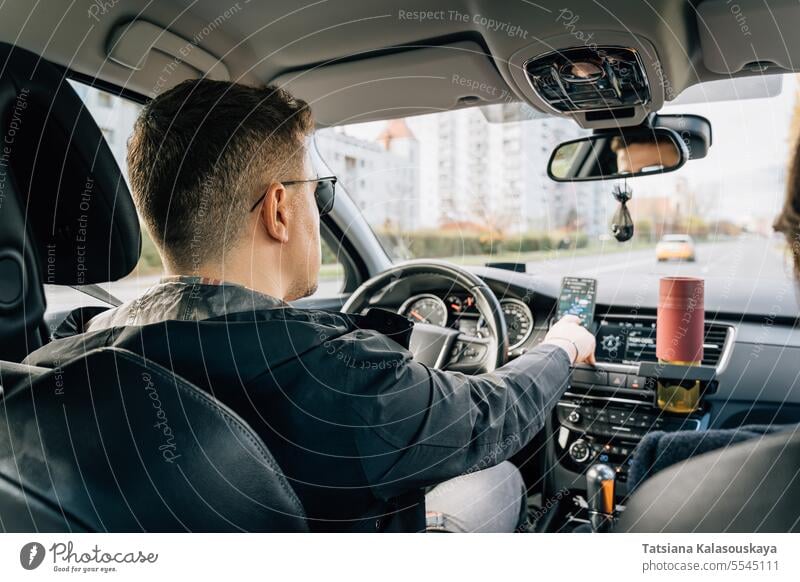 A man uses a phone installed in the cradle while driving Man Uses Navigator Application Cellphone Driving Car smartphone GPS Navigation by phone Driver