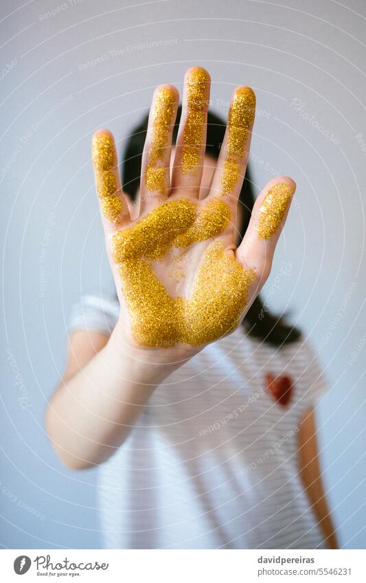Unrecognizable young girl showing her palm hand covered of golden glitter while doing stop sign unrecognizable micro plastic microplastics prohibition warning