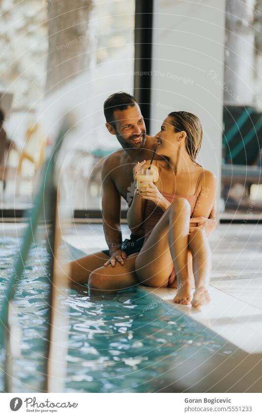 Young couple relaxing by the indoor swimming pool woman happy wellness female water adult love young caucasian enjoy poolside luxury beauty beautiful bikini