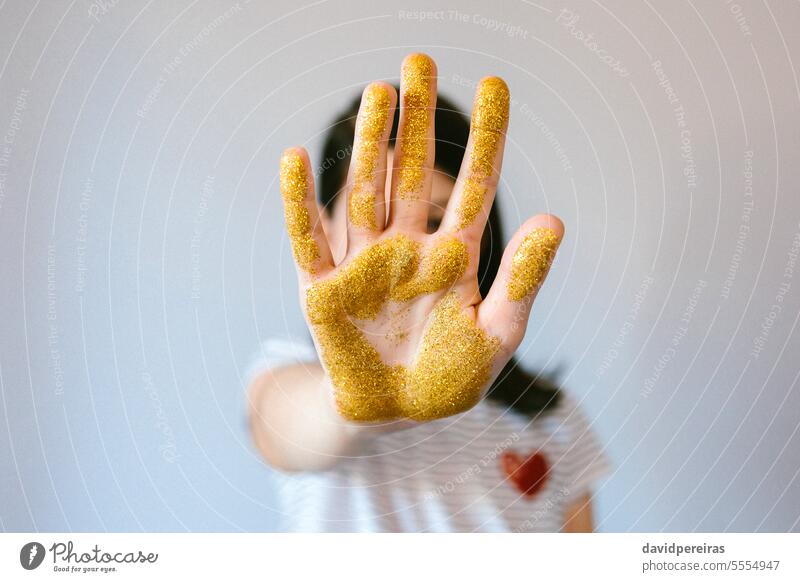 Unrecognizable young girl showing her palm hand covered of golden glitter while doing stop sign unrecognizable micro plastic microplastics prohibition european