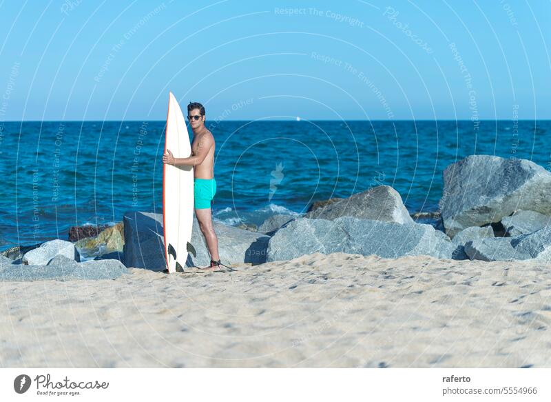 A man standing on the shore holding a surfboard - view from the back male person sport surfer lifestyle beach sea surfing sand ocean leisure water coast outdoor
