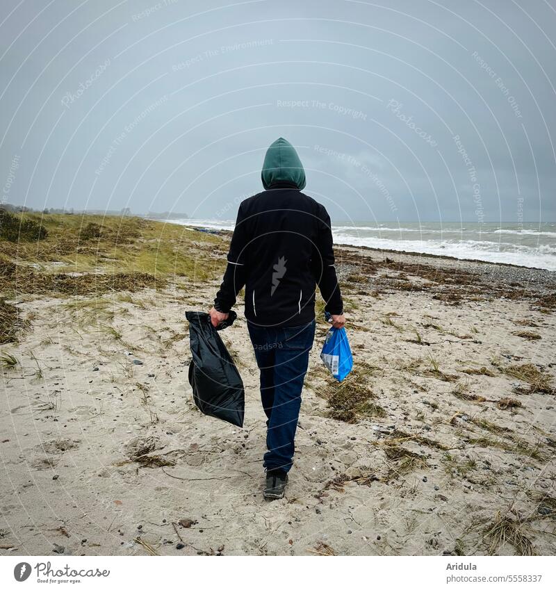 https://www.photocase.com/photos/5558337-man-walking-along-beach-with-two-bags-in-hand-to-collect-garbage-photocase-stock-photo-large.jpeg