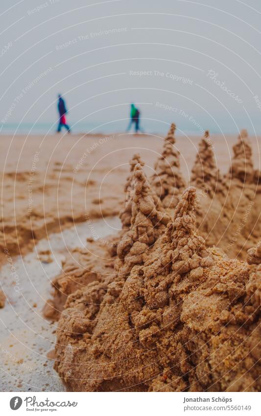 Beach walk behind sandcastle with towers on the beach in Warnemünde Walk on the beach Tourists Beach walkers Sandcastle protective wall vindicate rampart Autumn