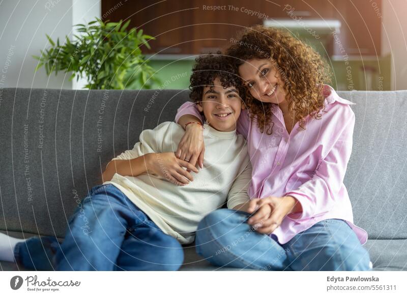 Happy mother and son sitting on sofa in living room at home real people adult apartment bonding boy child family female indoors kid lifestyle love mom