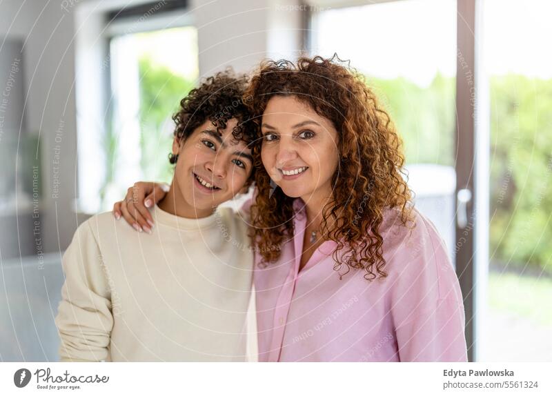 Portrait of smiling mother and son standing in living room at home real people adult apartment bonding boy child family female indoors kid lifestyle love mom