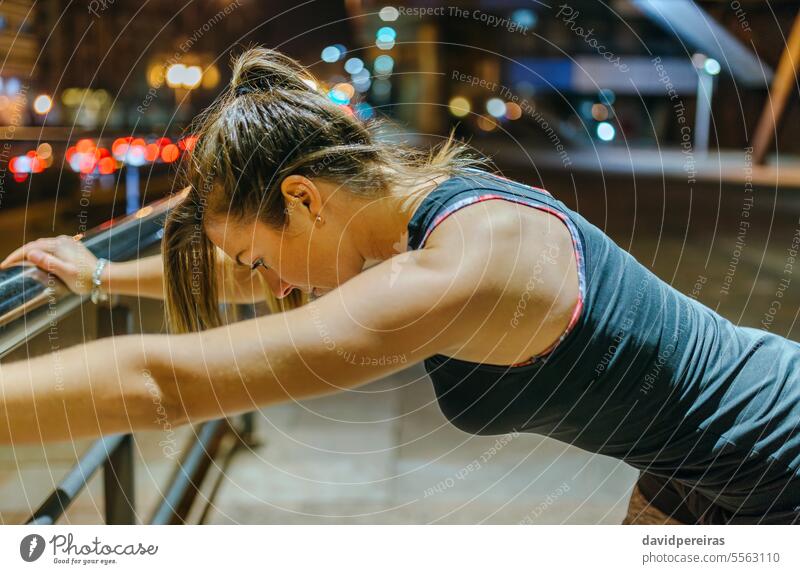 Portrait of female young athlete resting over banister after training at night in the city. exhausted tired runner woman running exhaustion fatigue break sweat