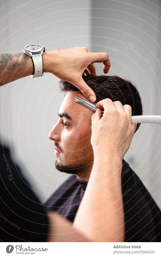 Barber cutting a client's hair with a razor. haircut shaping blade salon male focus care precision grooming technique professional barbershop man caucasian