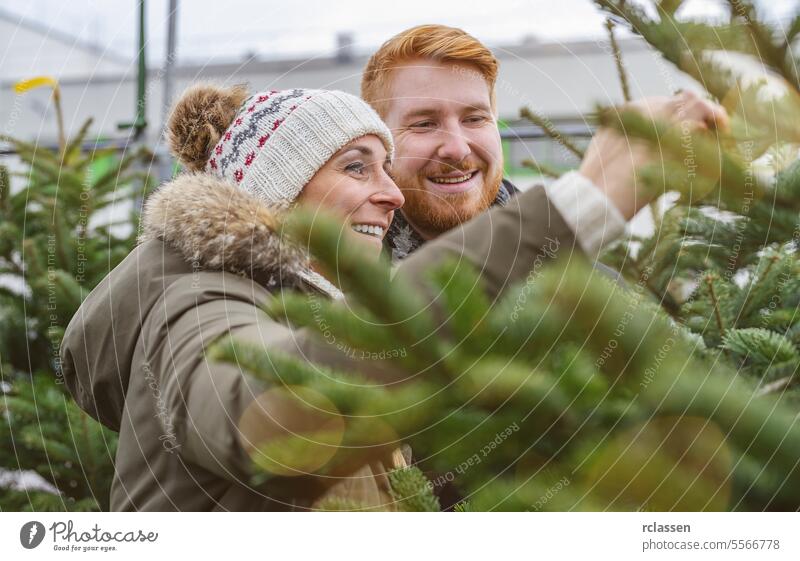 Happy couple selecting Christmas tree at X-mas fair surprised family happy skeptical redhead tradition choice smile man love couple purchase farm pine tree