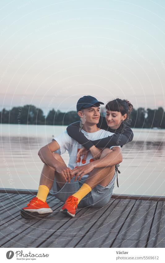 Cute young couple on the shore of a lake looking into their future during sunset. 20-year-old couple hugging together boyfriend girlfriend running almere