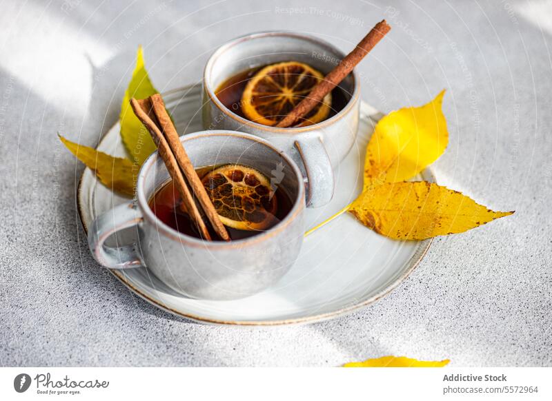 Spiced tea with autumn leaves spiced cup cinnamon anise dried orange slice leaf yellow beverage warm garnish gray surface ceramic drink aromatic fall seasonal