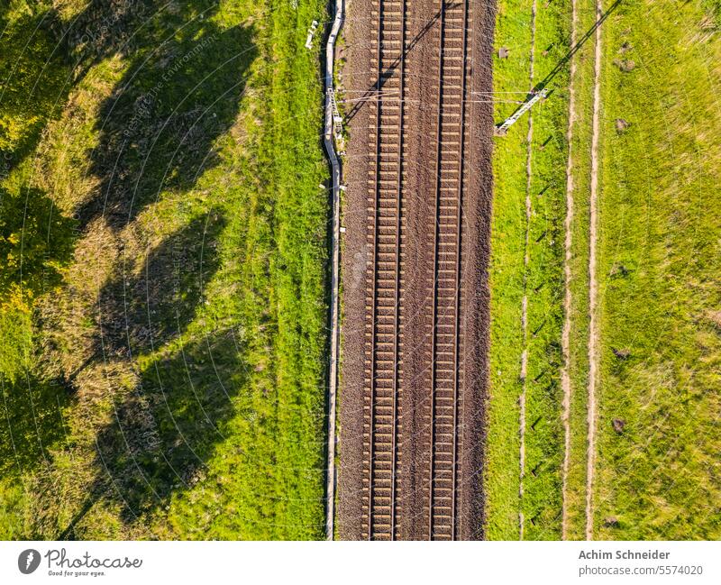 A railroad line in the countryside in the sun directly from above direct from above tracks train line two railroad tracks leads nature local passenger transport