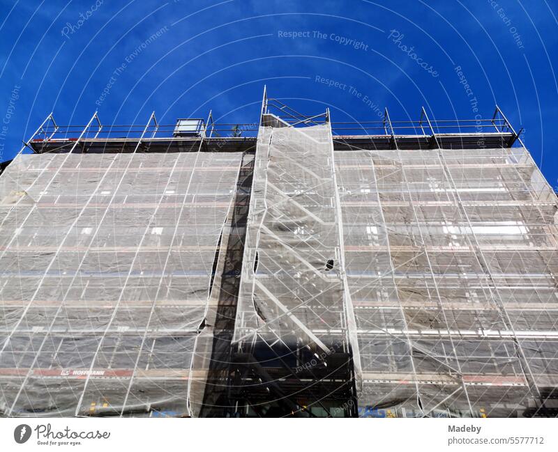 Scaffolding with safety net during the renovation of the facade of a large old building in front of a blue sky in sunshine in Bielefeld on Hermannsweg in the Teutoburg Forest in East Westphalia-Lippe