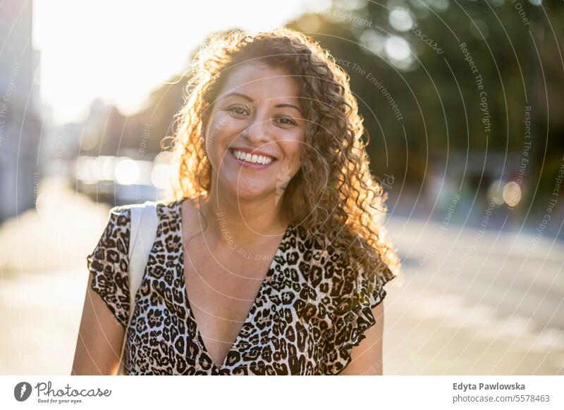 Portrait of a smiling young woman with curly hair in the city young adult street outside confidence enjoy laughing fun natural one person portrait expression