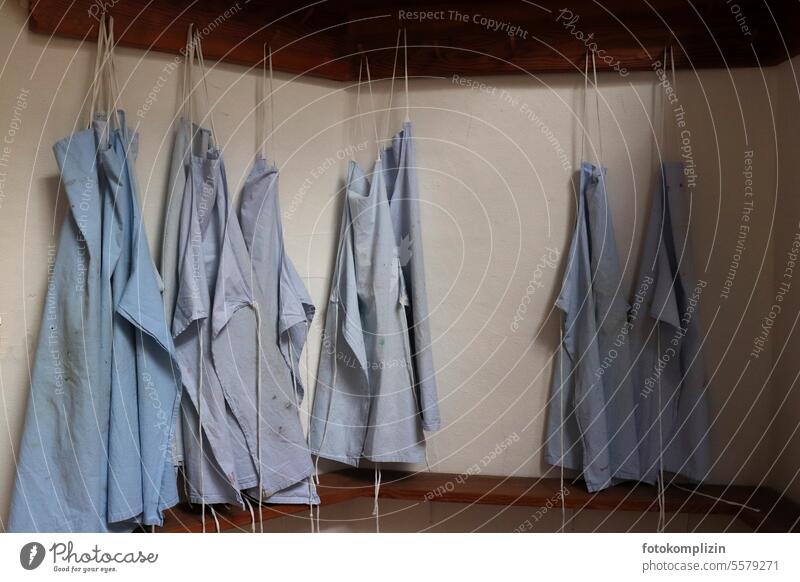 Light blue work coats at a checkroom Smock Apron overalls wardrobe Hang Clean apron dress Workshop labour hobby Arts and crafts Creativity creatively Together