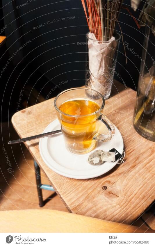 A glass of tea on a side table Tea Glass Teabag Cozy warm Beverage Hot drink Yellow Autumn Tea glass Herb tea saucers Saucer Healthy Wooden table Table