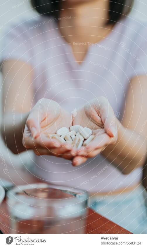 Close up shot of a woman holding many pills in her open hand, showing it to the camera suplement happy painkiller vitamin healthy pharmaceutical sick hospital