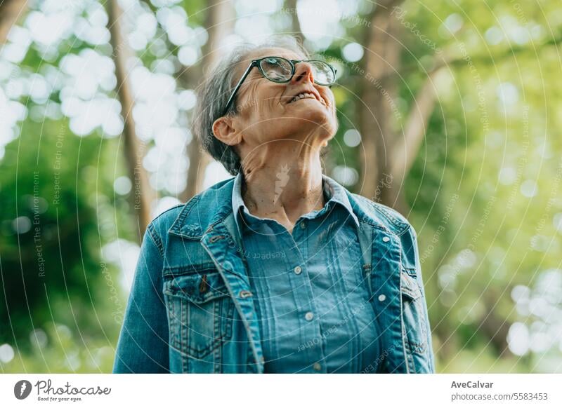 Portrait of older lady enjoying nature in forest, taking a walk breathing fresh air outside the city mental health woman retirement senior caucasian female