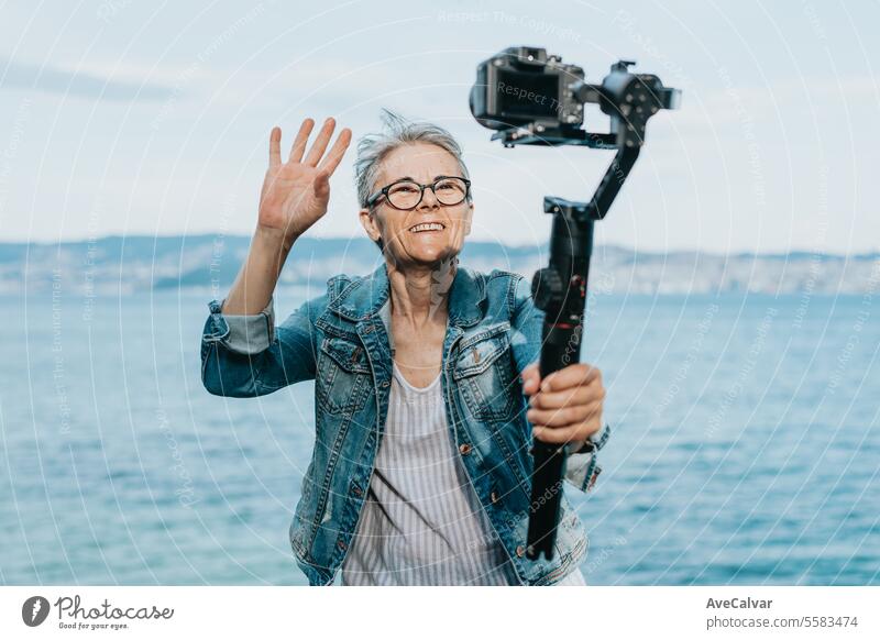 Senior joyful woman recording a video for her family explaining her vacation. Old photographer. senior retirement streamer live female lifestyle person young