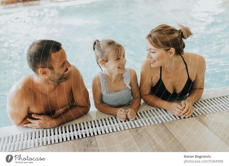 Family in the indoor swimming pool daughter three parent caucasian happy mother female water adult young kid enjoy boy happiness together people family fun