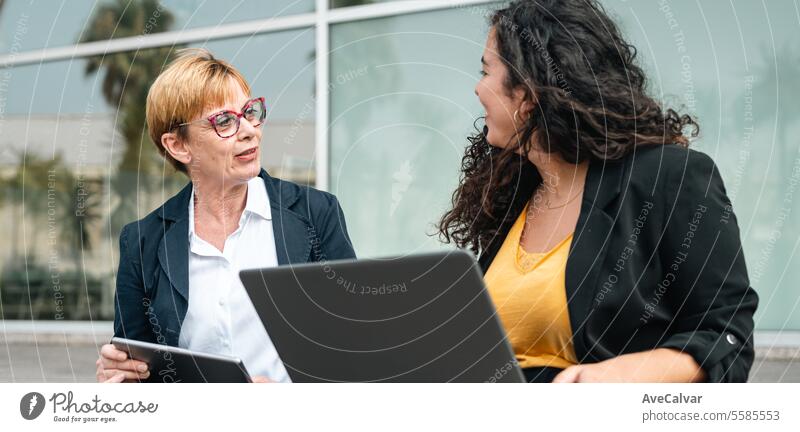 Business woman couple in front of office building sharing ideas during a brain storming. outdoors person business adult laptop businesswoman meeting teamwork