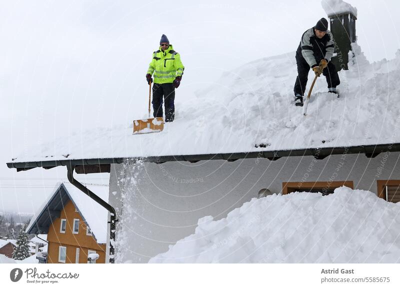 Two men shoveling high, heavy snow from the roof of a house snowplough Snow Winter snow shovels Roof House (Residential Structure) house roof snow-laden Weight