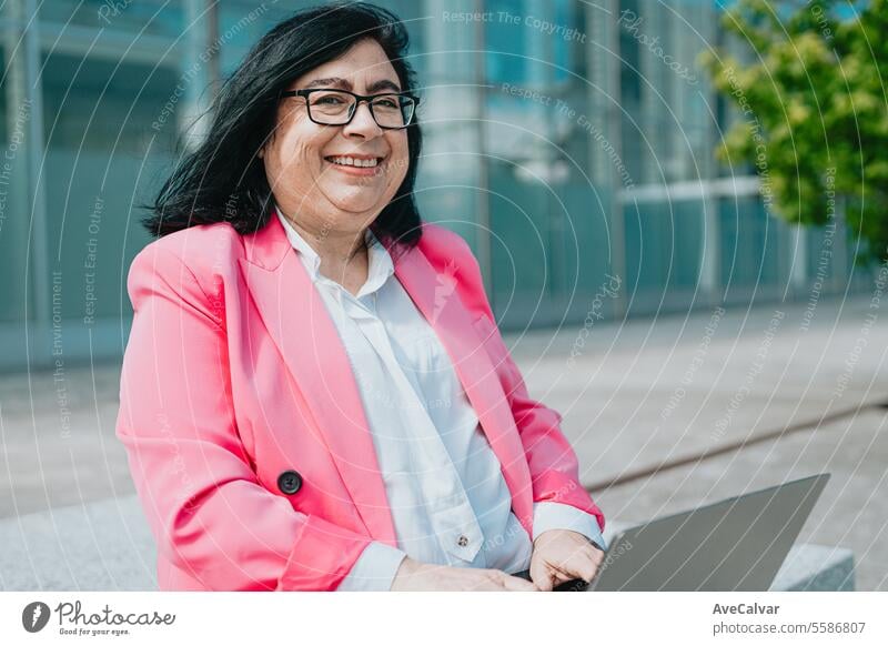Woman in pink blazer searching for information on her laptop while taking a break from work outdoors female person women adult smile happy lady portrait young