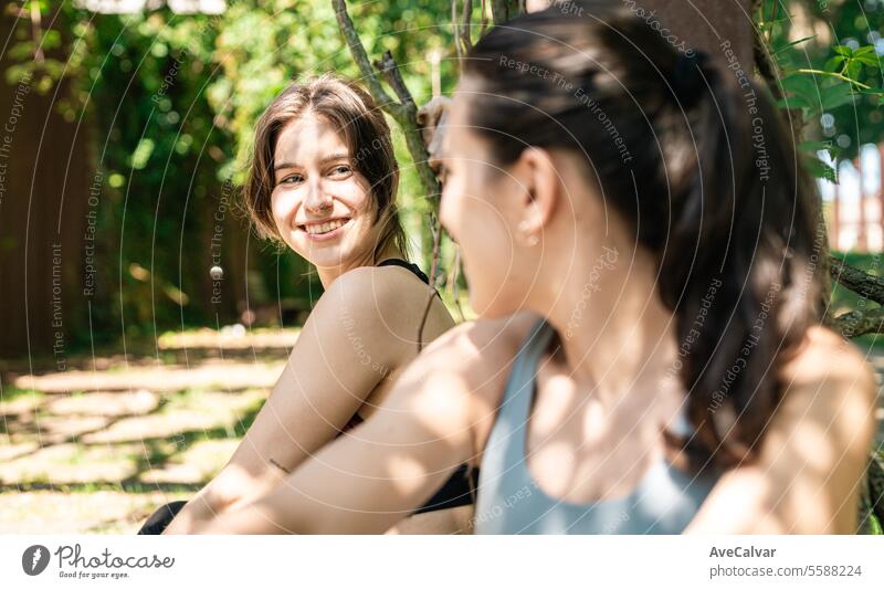 Two young fit cheerful girls sitting rested after doing sports happy to achieve their sports goals. lifestyle female women person beauty healthy caucasian